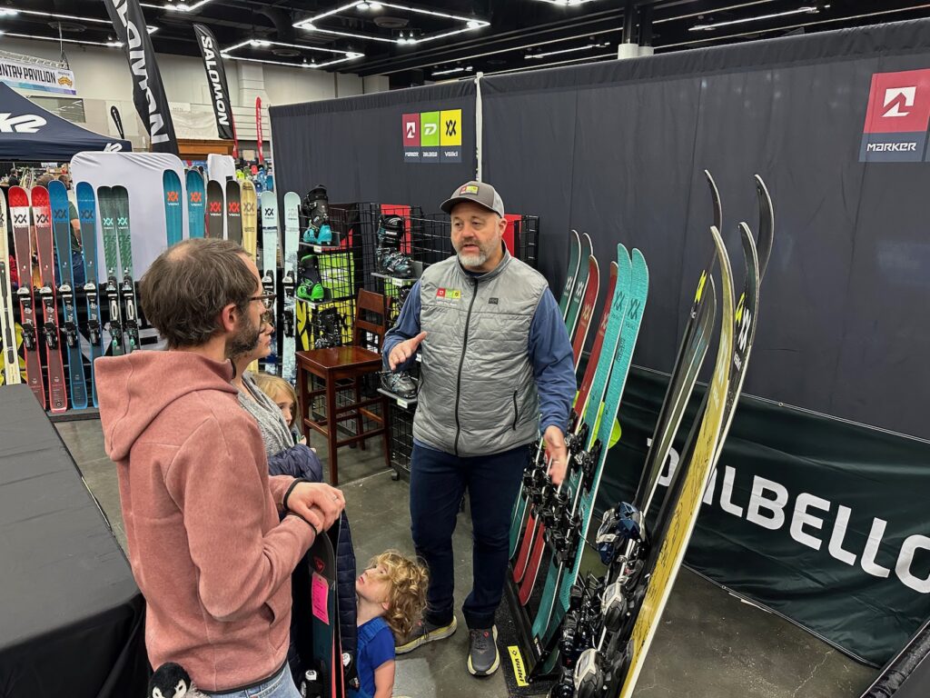 a gear rep talking about skis to a couple at Snowvana
